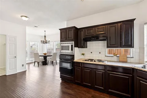 a kitchen with stainless steel appliances a sink dishwasher a stove refrigerator and cabinets with wooden floor