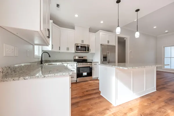 a kitchen with kitchen island a sink stainless steel appliances and a counter top space