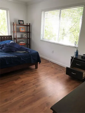a bedroom with a bed window and a wooden floor