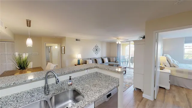 a kitchen with stainless steel appliances granite countertop a refrigerator a stove and a sink with wooden floor