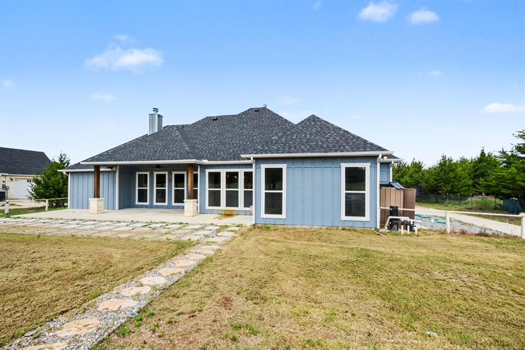 530 P R 491 Leonard, TX 75452 - Photo 32 of 35 Rear exterior featuring a covered patio with stone-wrapped pillars, a stone paver patio, a stepping stone pathway, and a shingled roof