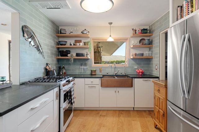 a kitchen with stainless steel appliances granite countertop a refrigerator a stove and a sink with wooden floor