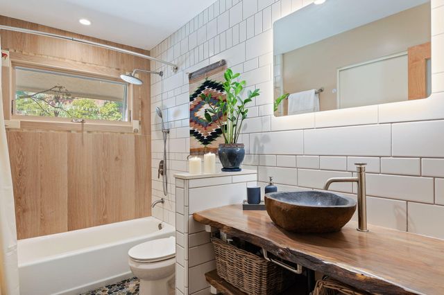 a bathroom with a granite countertop sink a toilet a mirror and shower