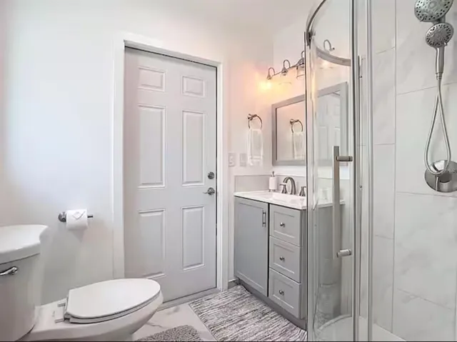 a bathroom with a granite countertop sink a toilet and shower