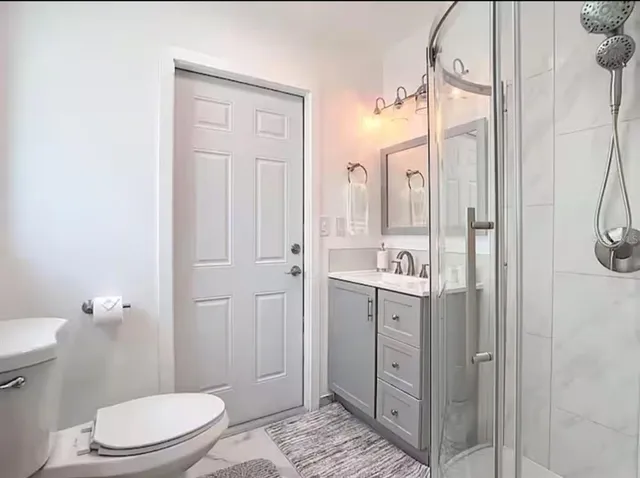 a bathroom with a granite countertop sink a toilet and shower