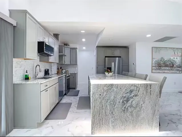 a kitchen with stainless steel appliances granite countertop a stove top oven a sink dishwasher and cabinets with wooden floor