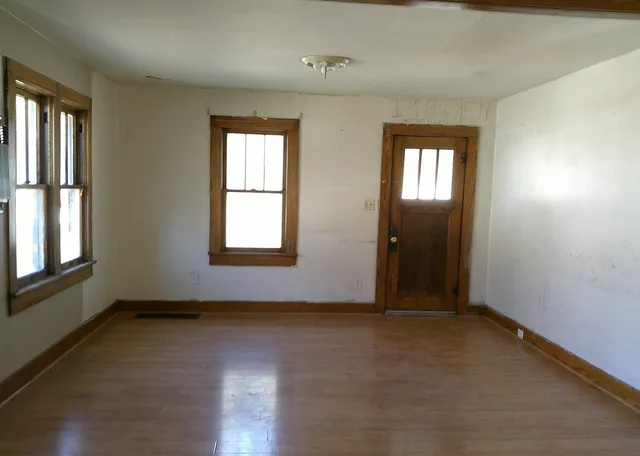 an empty room with wooden floor and windows
