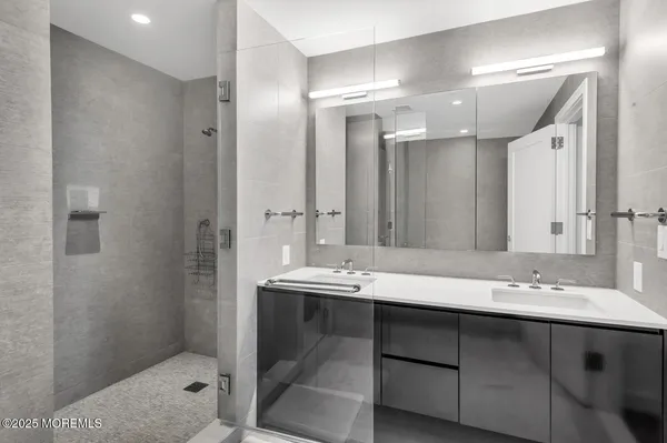 a bathroom with a sink shower and a mirror