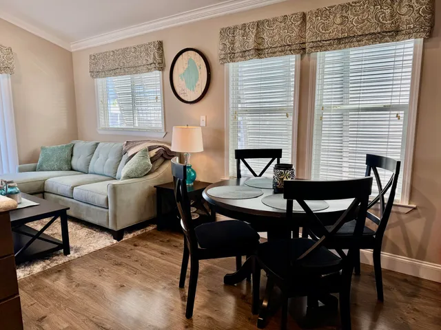 a kitchen with a sink dishwasher a stove a microwave oven and a dining table with wooden floor