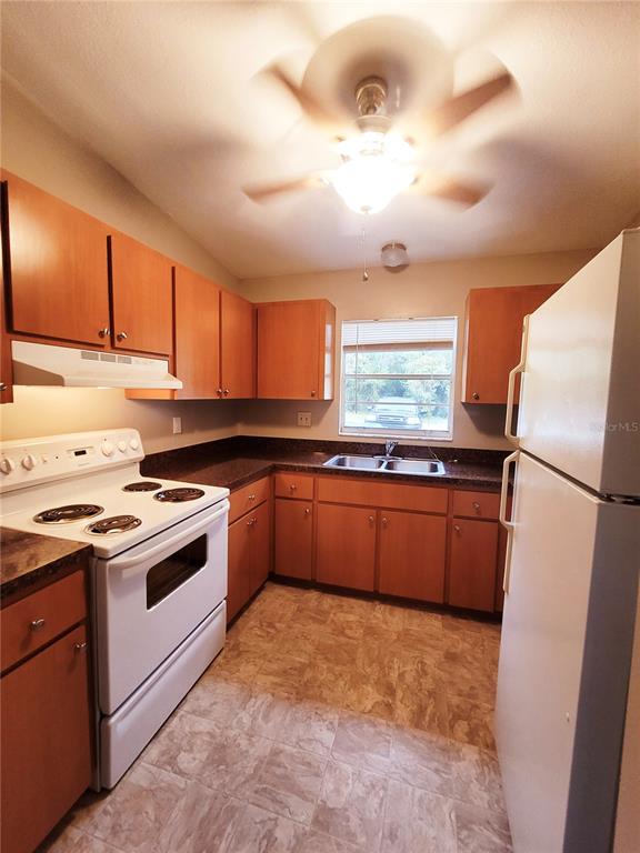 4331 Azora Road Spring Hill, FL 34608 - Photo 5 of 16 a kitchen with granite countertop a refrigerator stove top oven a sink and dishwasher