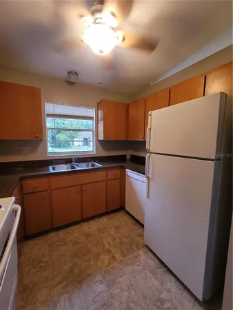 a kitchen with granite countertop a refrigerator a sink a stove a dining table and chairs