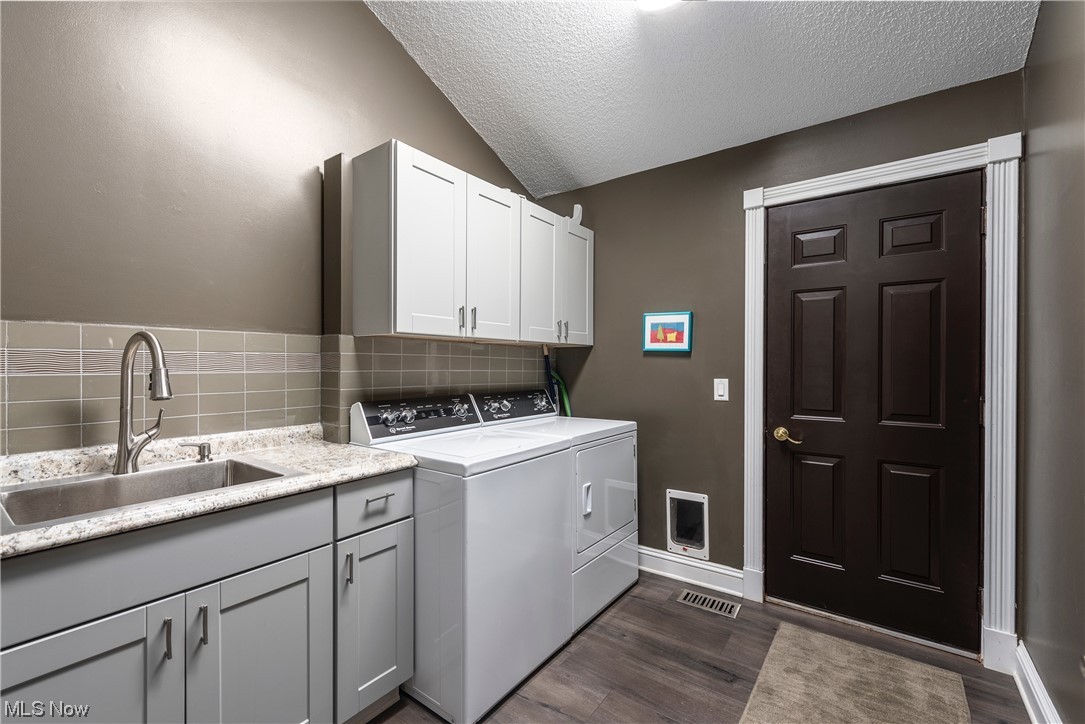 3718 Fenn Road Medina, OH 44256 - Photo 23 of 35 Clothes washing area with sink, washing machine and clothes dryer, a textured ceiling, dark wood-type flooring, and cabinets
