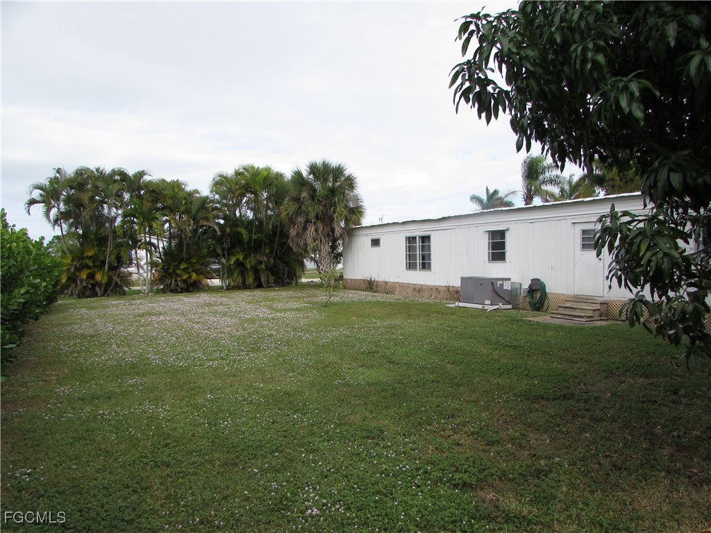 7711 Farrell Road Bokeelia, FL 33922 - Photo 6 of 21 a view of a white house in front of a big yard with plants and large trees
