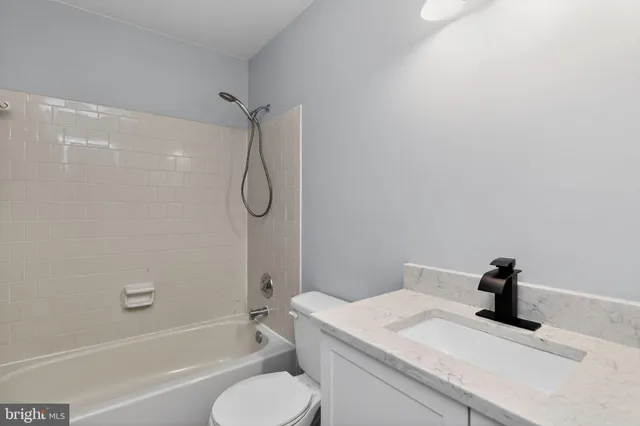 a bathroom with a granite countertop bathtub shower sink vanity and toilet