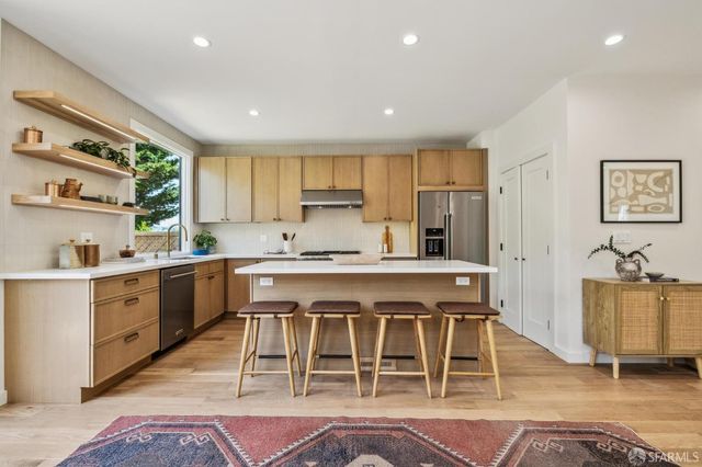 a kitchen with kitchen island a stove a refrigerator and island with wooden floors