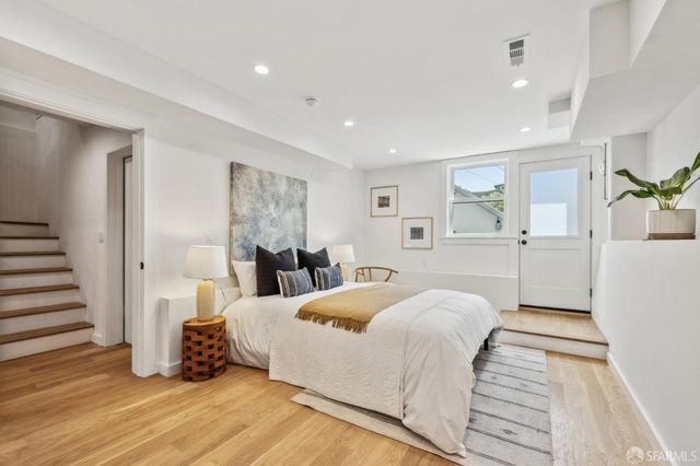a spacious bedroom with a bed and wooden floor