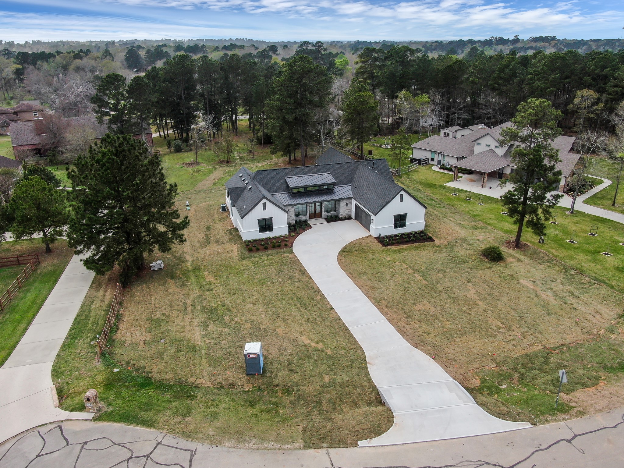 14742 Turquoise Trail Willis, TX 77378 - Photo 41 of 48 Aerial view showcasing the custom modern farmhouse situated on a spacious 1.04-acre homesite with a sweeping driveway and mature trees surrounding the property.