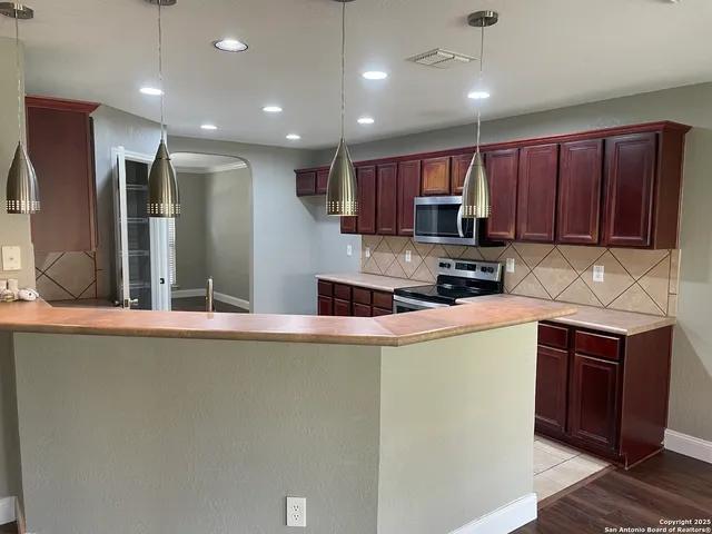 a kitchen with stainless steel appliances granite countertop a refrigerator a sink a stove a microwave and wooden cabinets