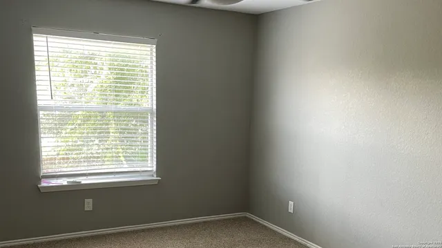 an empty room with windows and chandelier fan