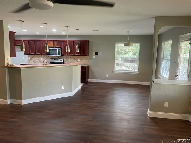 a kitchen with stainless steel appliances granite countertop a refrigerator a sink dishwasher a stove and a wooden cabinets with wooden floor