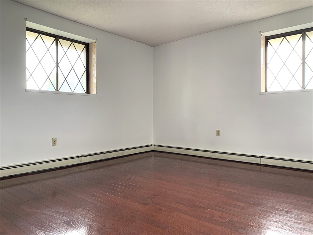 301 Lowell Street, Unit 34 Somerville, MA 02145 - Photo 11 of 15 an empty room with wooden floor and windows