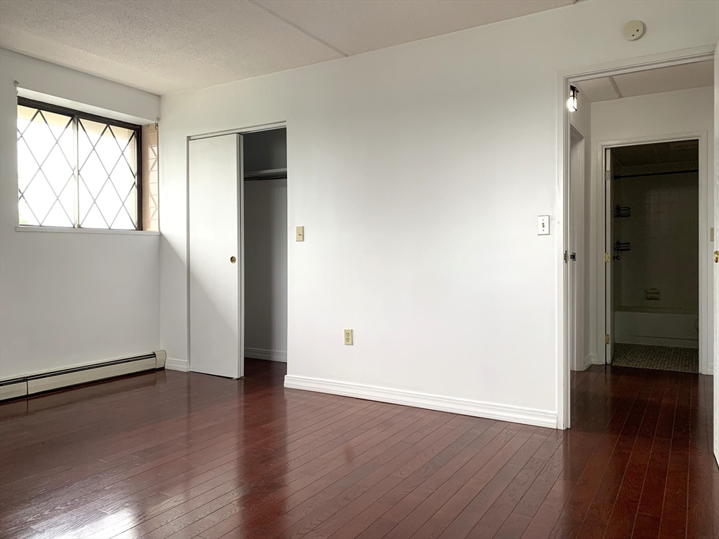 301 Lowell Street, Unit 34 Somerville, MA 02145 - Photo 13 of 15 an empty room with wooden floor and windows