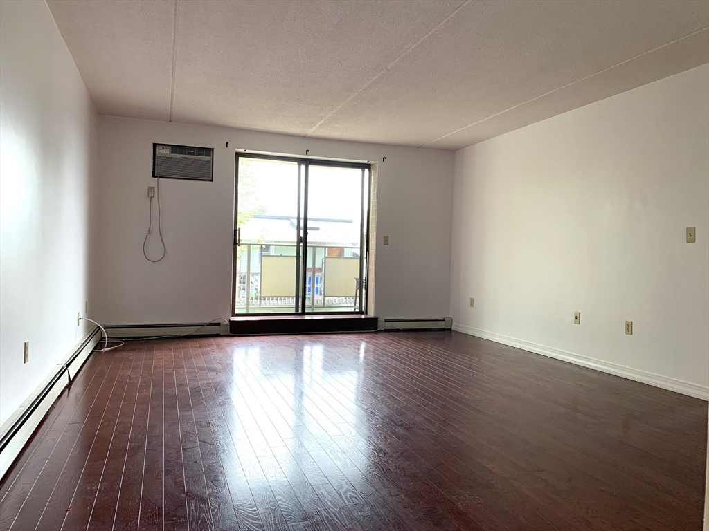 301 Lowell Street, Unit 34 Somerville, MA 02145 - Photo 5 of 15 an empty room with wooden floor and windows
