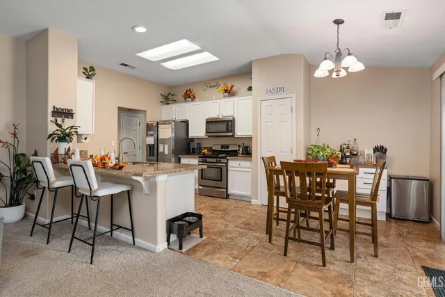 a dining room filled chandelier and kitchen view