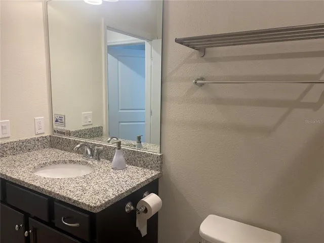 a bathroom with a granite countertop sink and a mirror