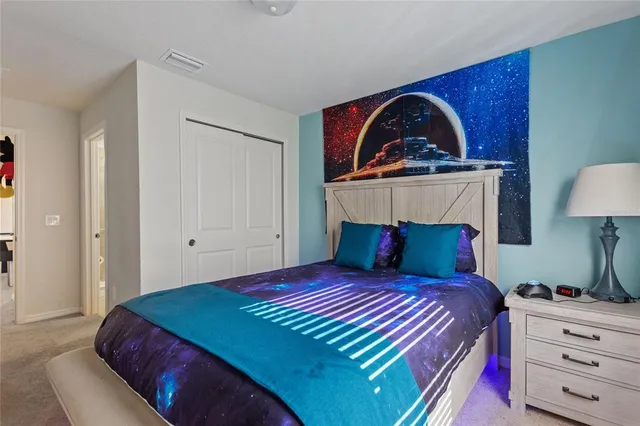 a bedroom with a bed and a lamp on dresser