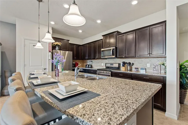 a kitchen with sink refrigerator dining table and chairs
