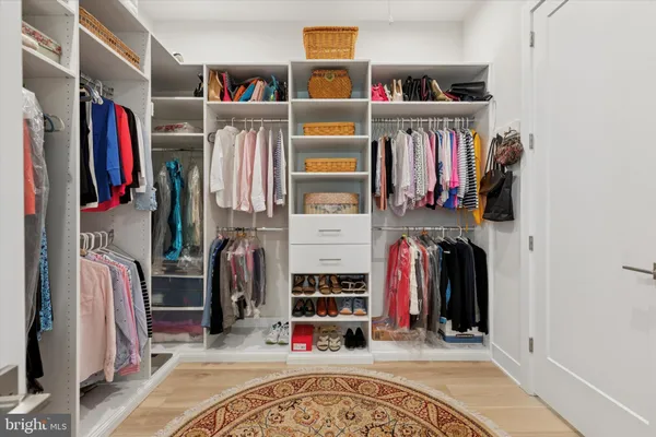 a view of walk in closet with clothes and shoes