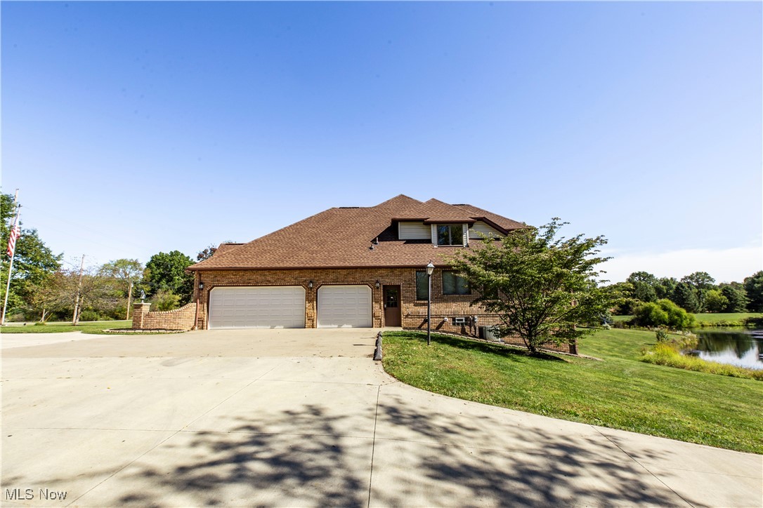 1570 Reimer Road Wadsworth, OH 44281 - Photo 43 of 48 View of front facade featuring concrete driveway, brick siding, a front lawn, a garage, and a water view