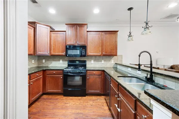 a kitchen with stainless steel appliances granite countertop a sink stove and cabinets