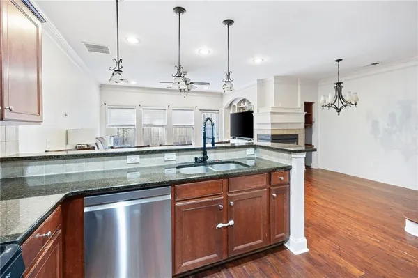 a kitchen with stainless steel appliances granite countertop a sink a stove and a wooden floor