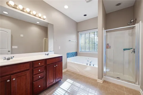 a spacious bathroom with a tub double sink shower and mirror