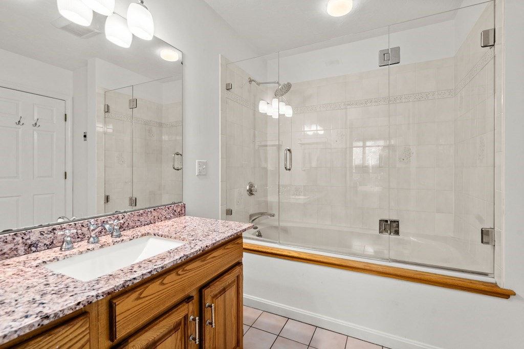 53 South Walnut Street, Unit 2 Quincy, MA 02169 - Photo 15 of 24 a bathroom with a granite countertop sink a mirror and a bathtub