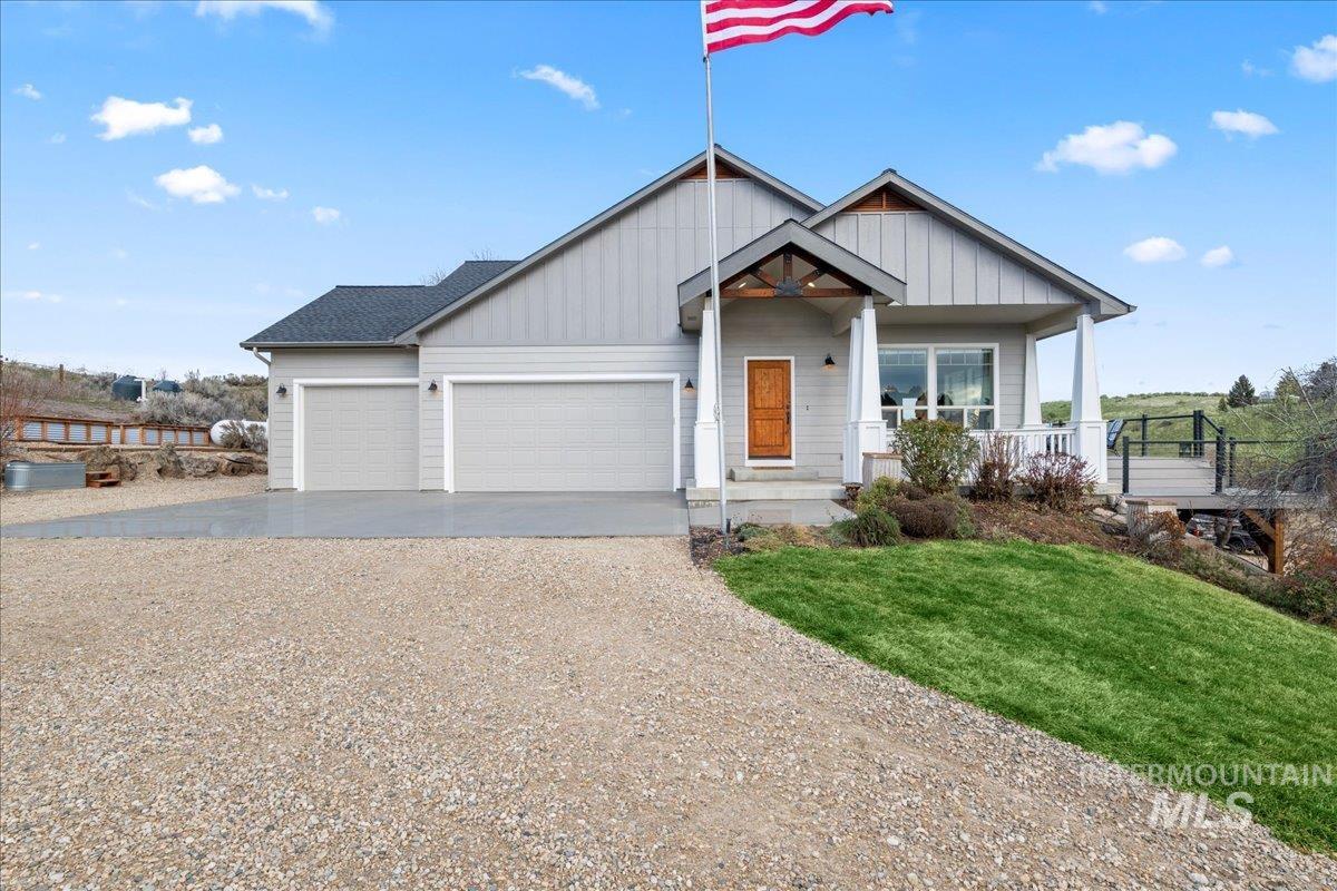 View of front of home featuring driveway, covered porch, a front yard, and board and batten siding