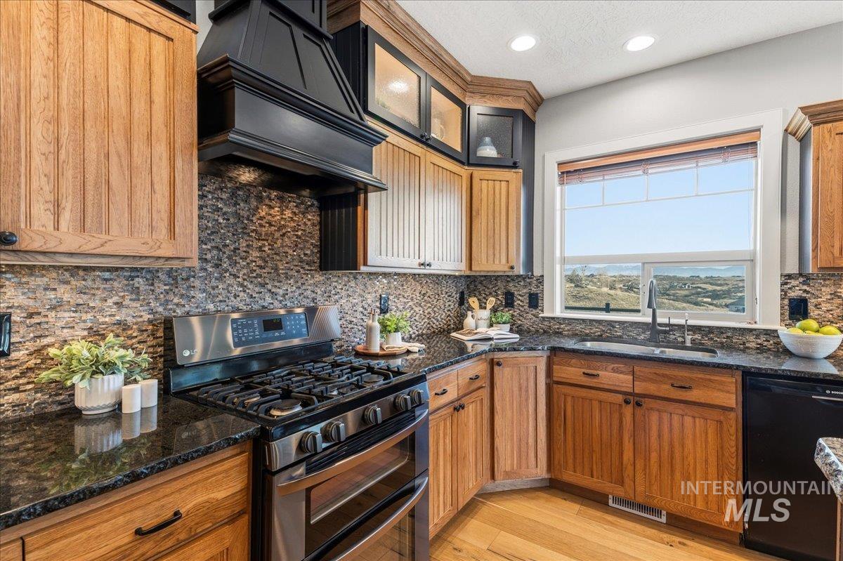 7434 Lanktree Lane Middleton, ID 83644 - Photo 11 of 34 Kitchen with range with two ovens, black dishwasher, dark stone counters, light wood-style flooring, and custom exhaust hood