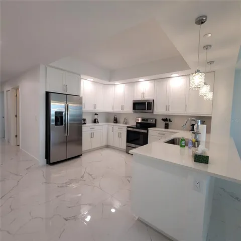 a large white kitchen with lots of counter space white cabinets and stainless steel appliances