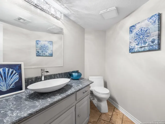 a bathroom with a granite countertop sink mirror vanity and toilet