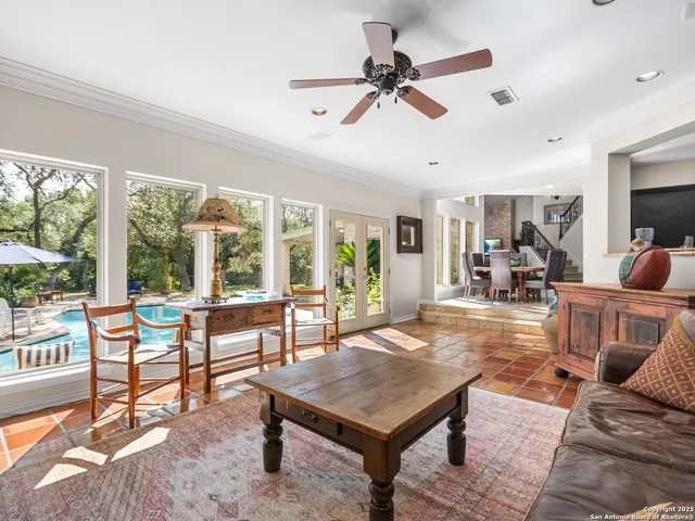 a living room with furniture a ceiling fan and a large window