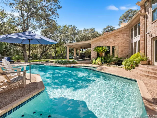 a view of a swimming pool with lawn chairs under an umbrella