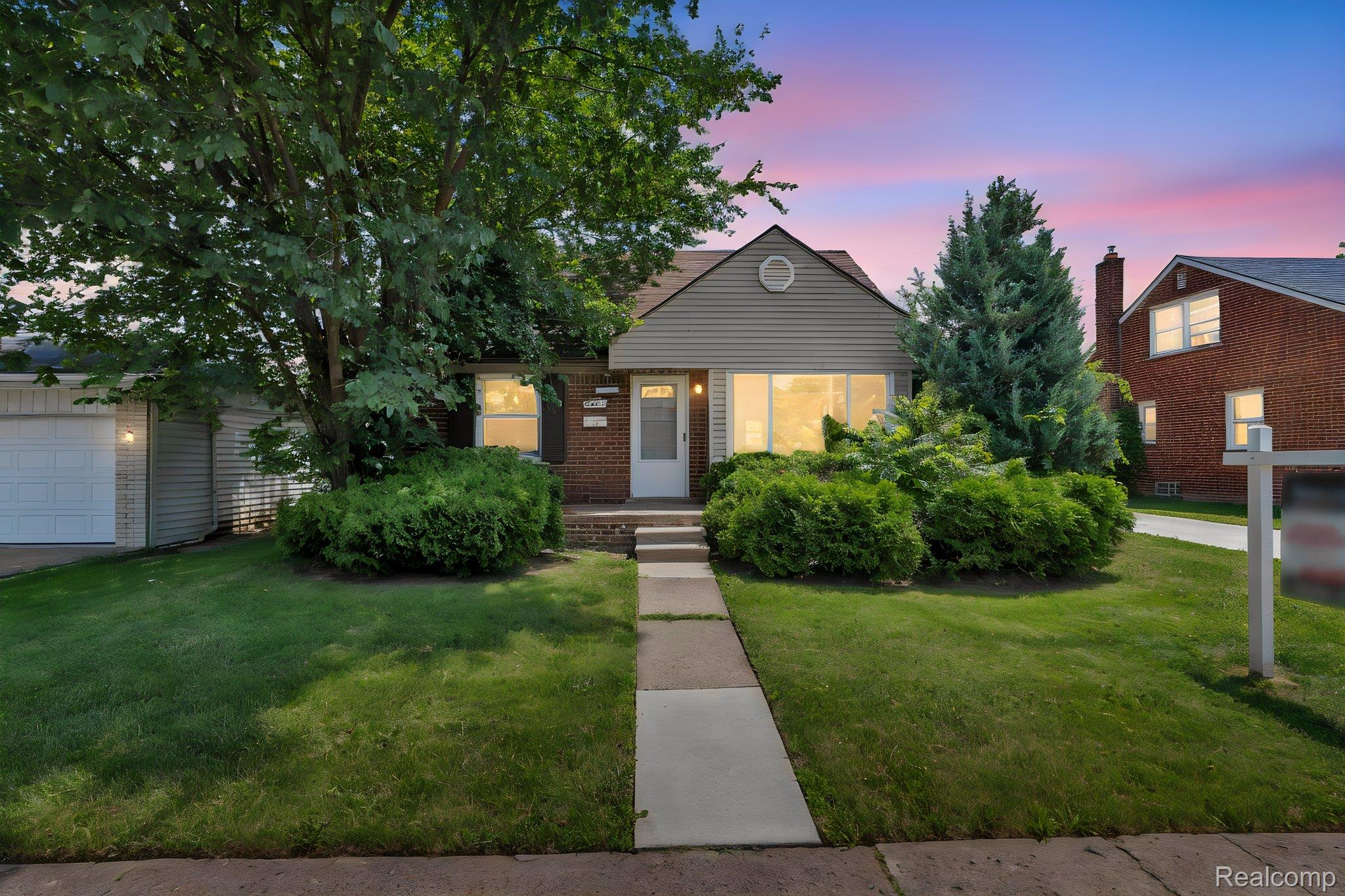 7641 Pelham Road Allen Park, MI 48101 - Photo 1 of 21 Front exterior featuring a combination of brick and siding, a concrete pathway, a garage with a white door, and established shrubbery