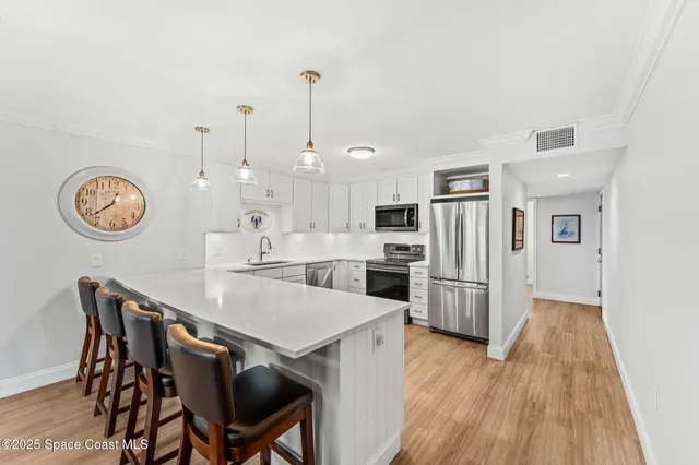 a view of a dining room and livingroom with furniture wooden floor a chandelier