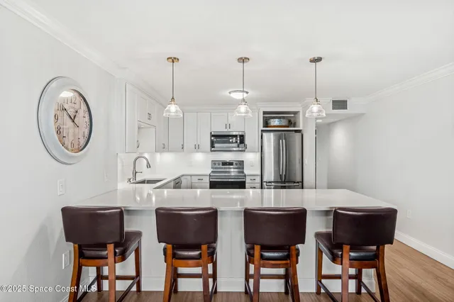 a kitchen with stainless steel appliances a dining table chairs and white cabinets