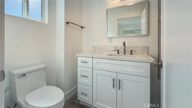 a bathroom with a toilet sink vanity and mirror