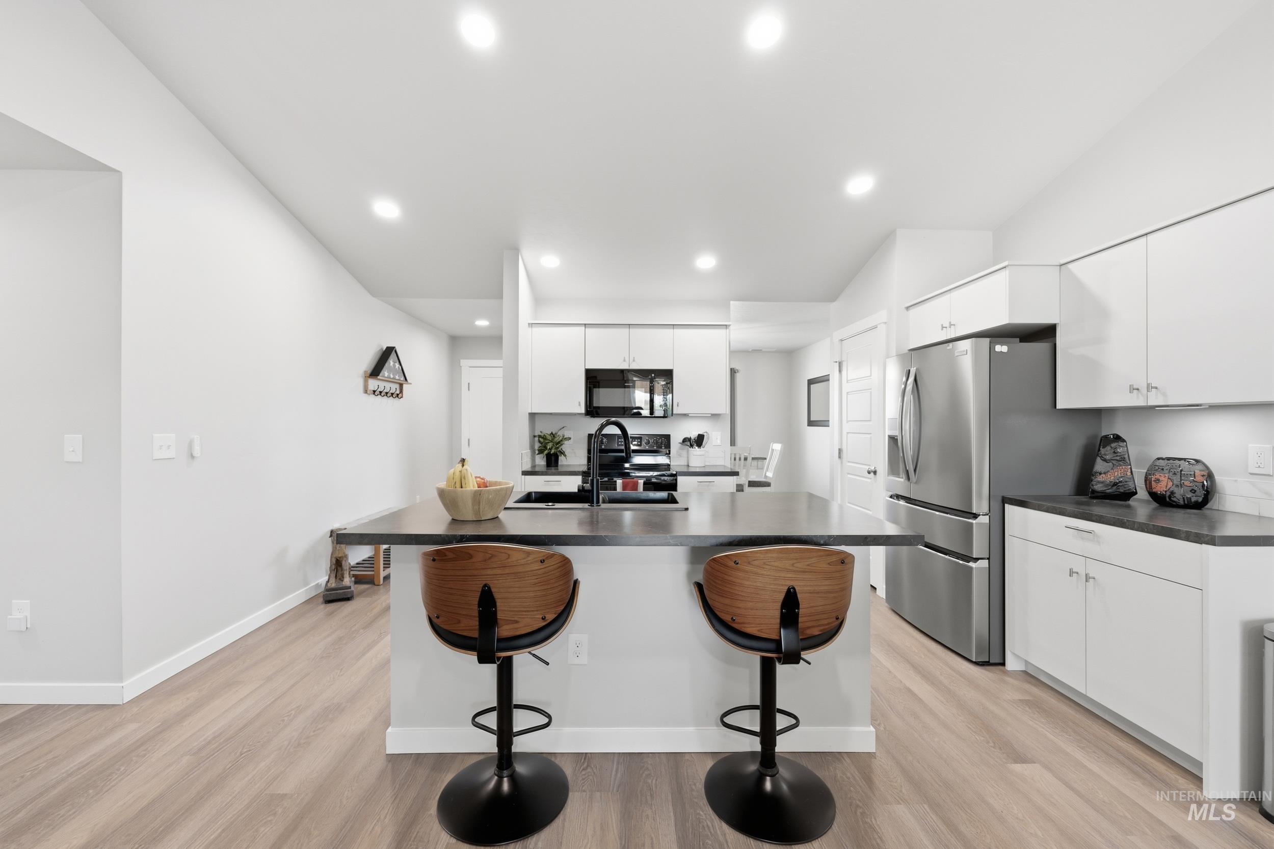 3697 W Lane Meridian, ID 83642 - Photo 12 of 44 Kitchen with white cabinetry, a breakfast bar area, dark countertops, a kitchen island with sink, and recessed lighting