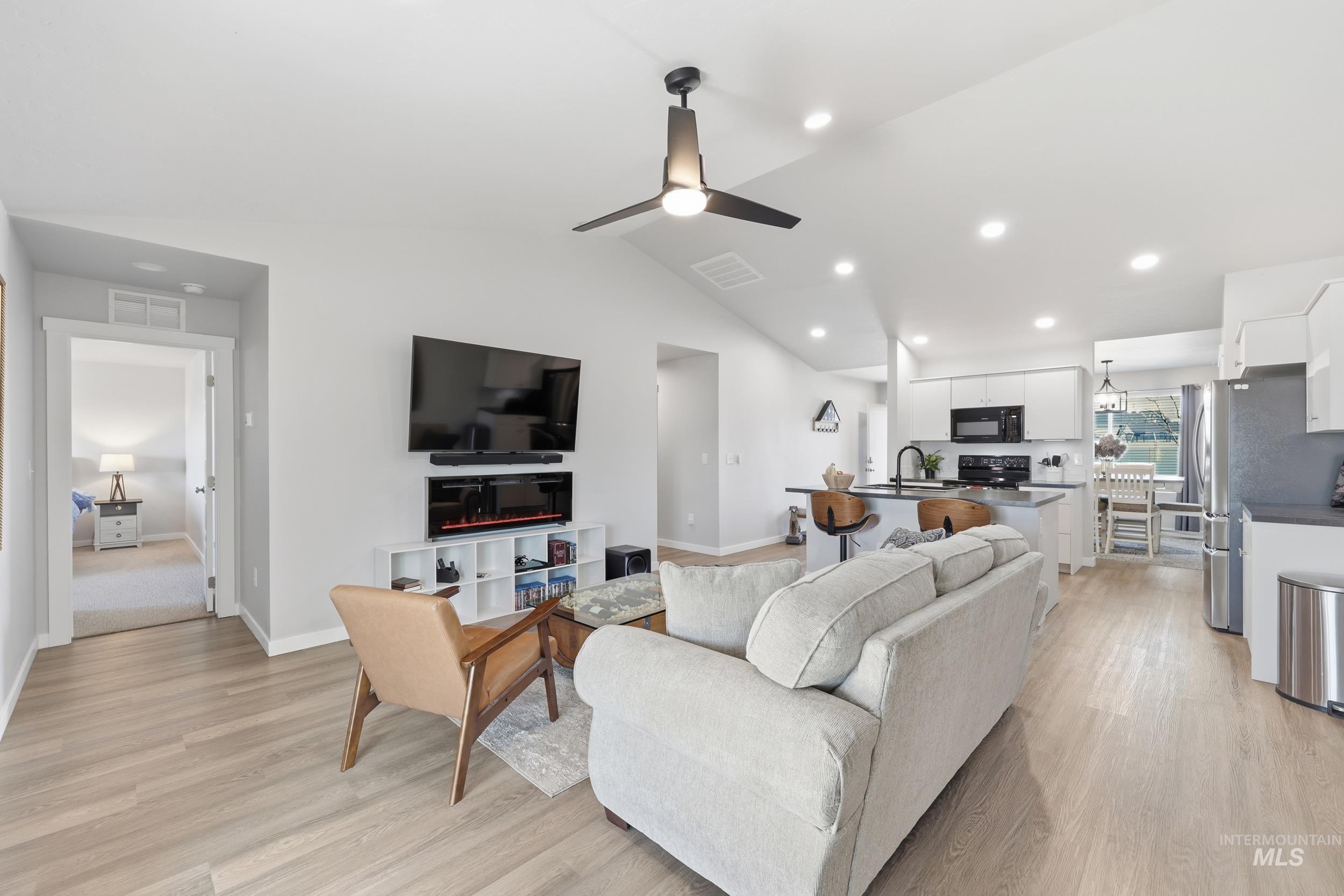 3697 W Lane Meridian, ID 83642 - Photo 20 of 44 Living room featuring ceiling fan, LVP Floroing, vaulted ceiling, and recessed lighting. Electric Fireplace