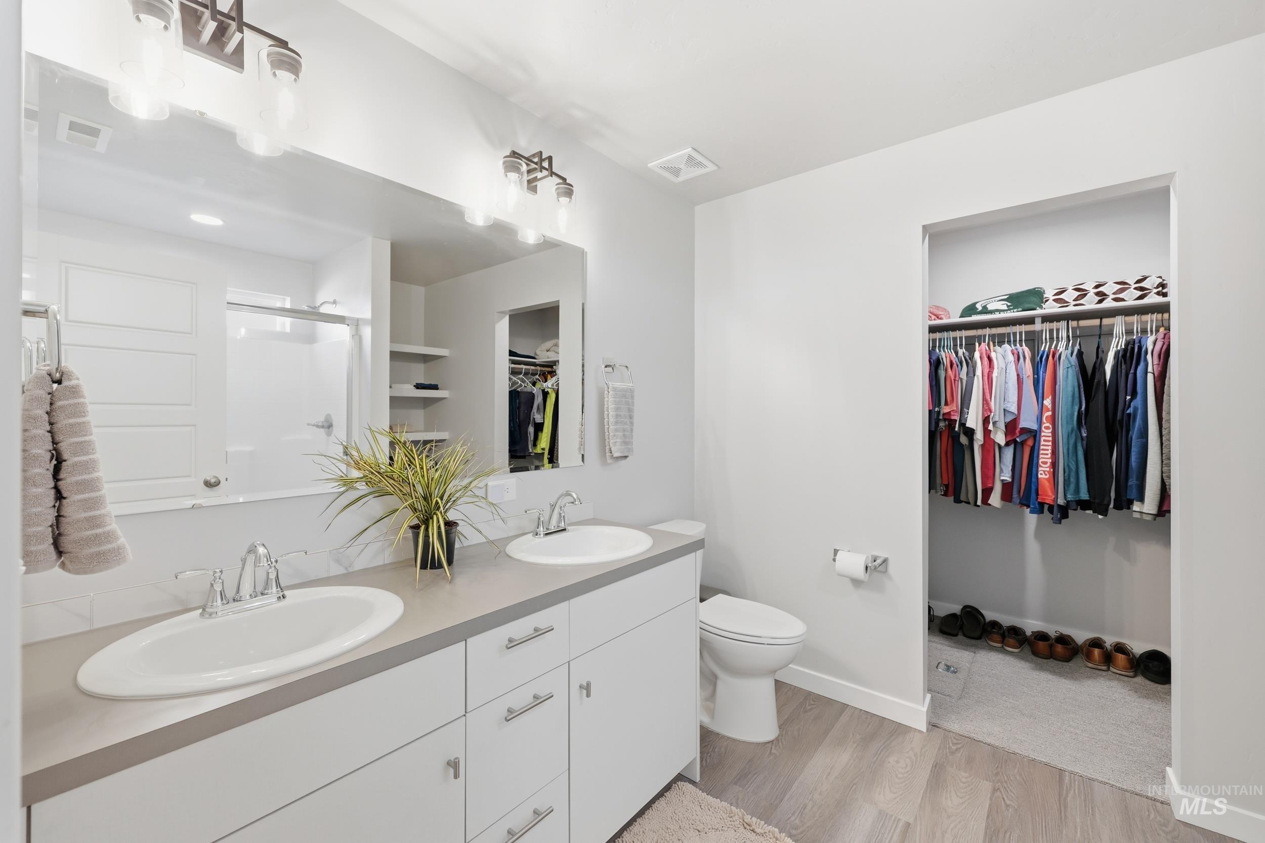3697 W Lane Meridian, ID 83642 - Photo 26 of 44 Bathroom with a spacious walk in closet, linen storage shelf, double vanity, LVP floors, and a step in shower.